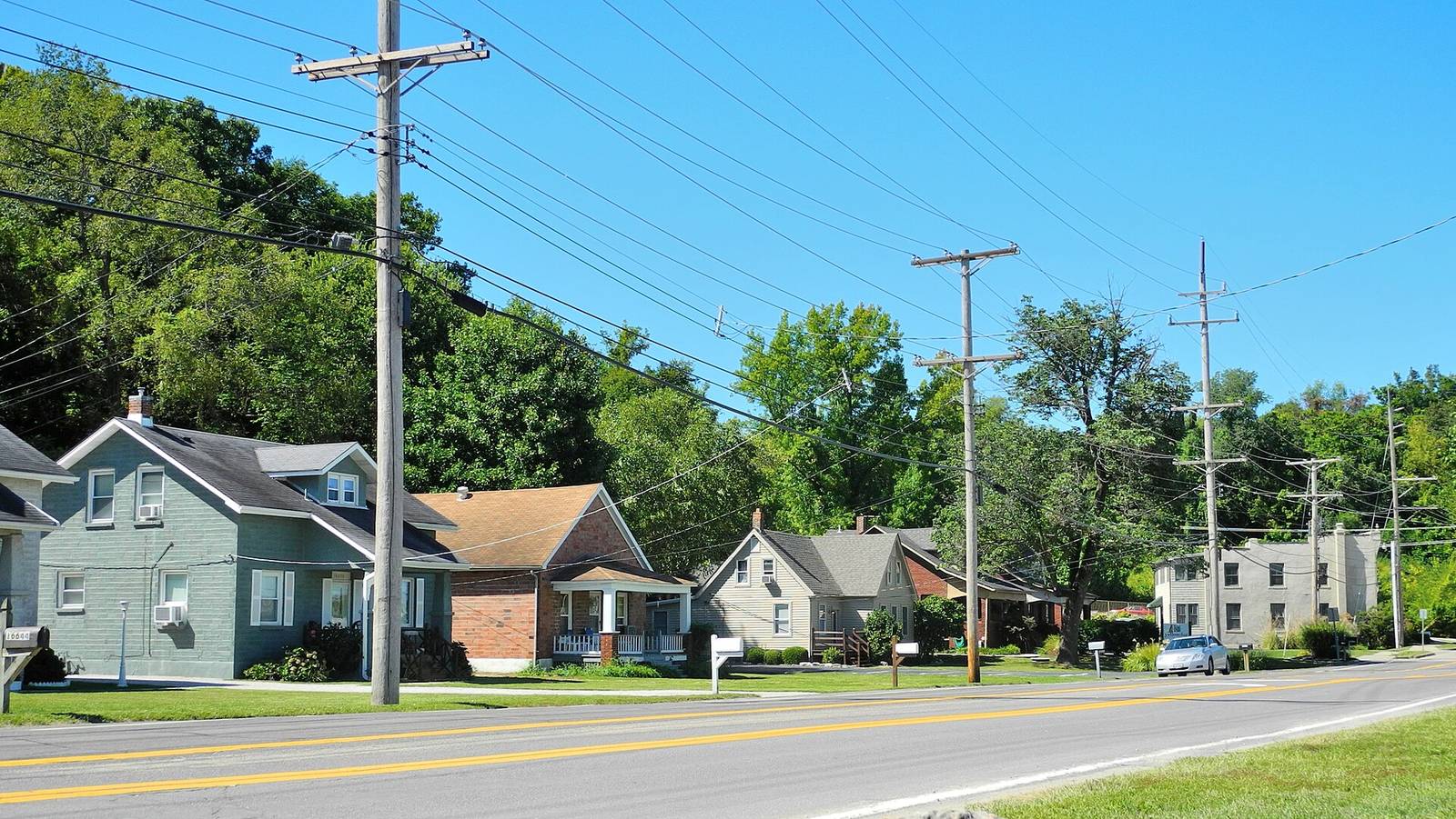 Old Chesterfield on Olive Street Road, small houses and utility poles under a bright summer sky on the bluff side of town.